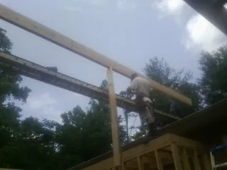 Carpenter setting a ridge beam over a new addition frame — Ice Dam Removal by Roofing Brothers in Fletcher
